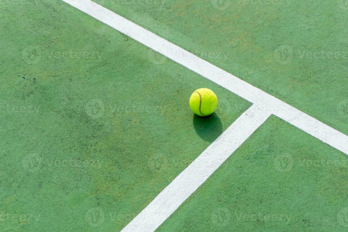 Yellow tennis ball on green court and white lines. Top angle view of tennis ball on court. photo