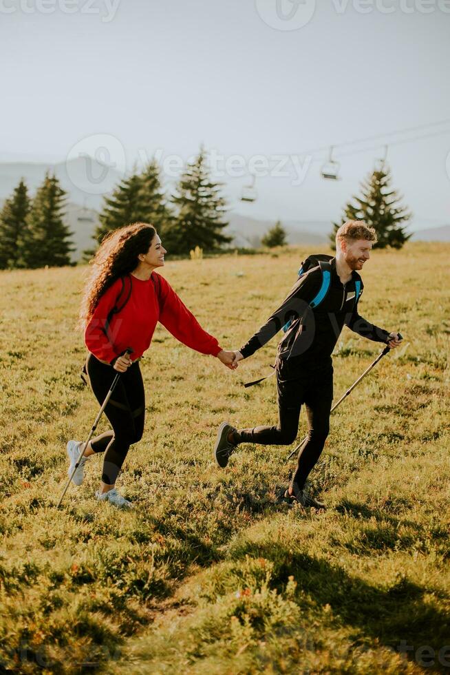 Young couple walking with backpack over green hills photo