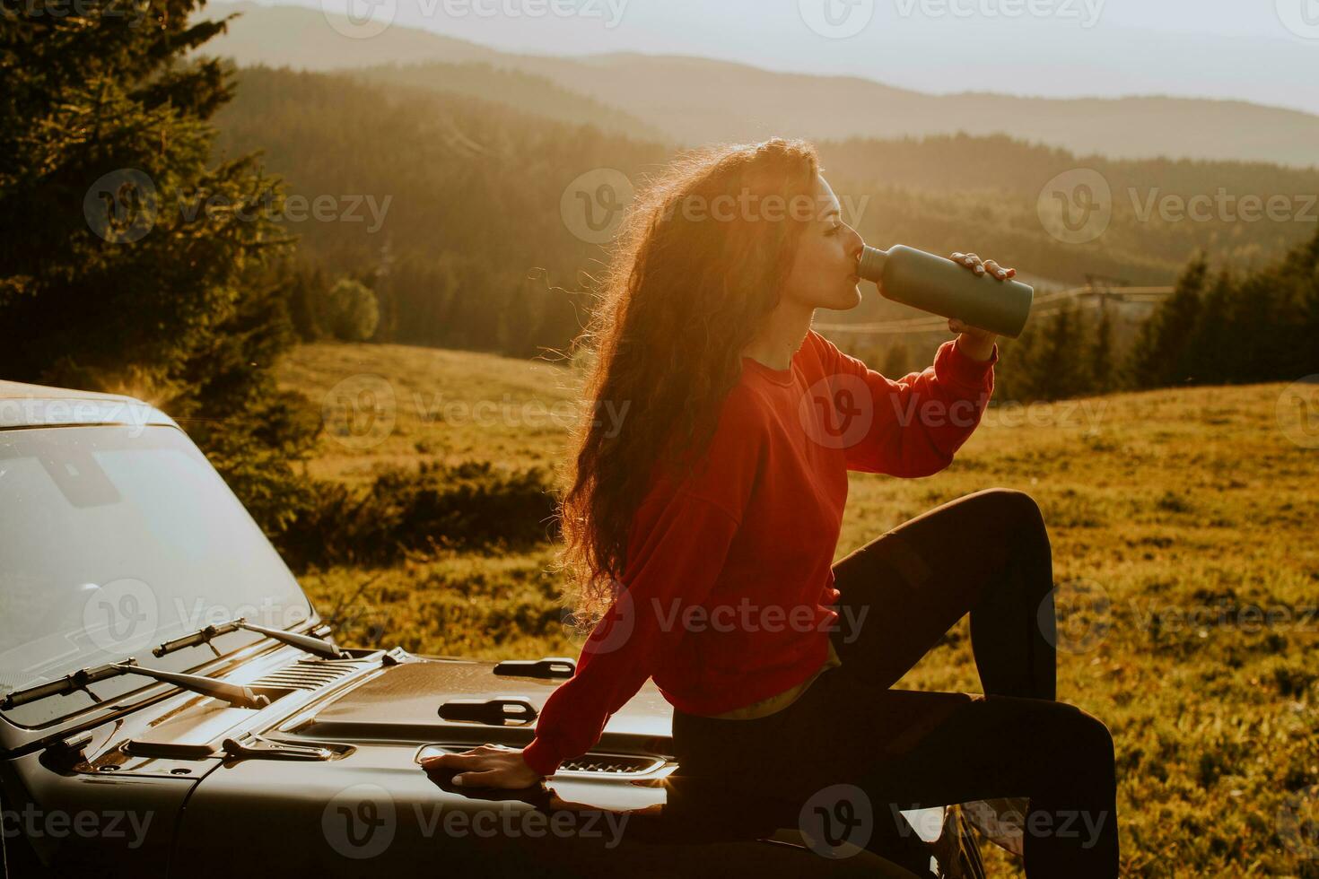 Young woman relaxing on a terrain vehicle hood at countryside photo