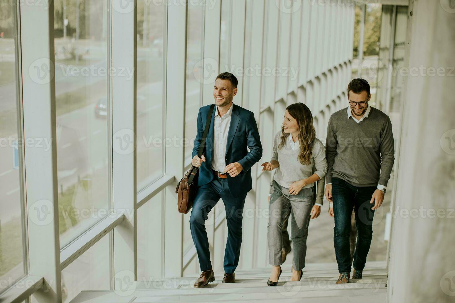 Group of corporate business professionals climbing at stairs in office corridor photo