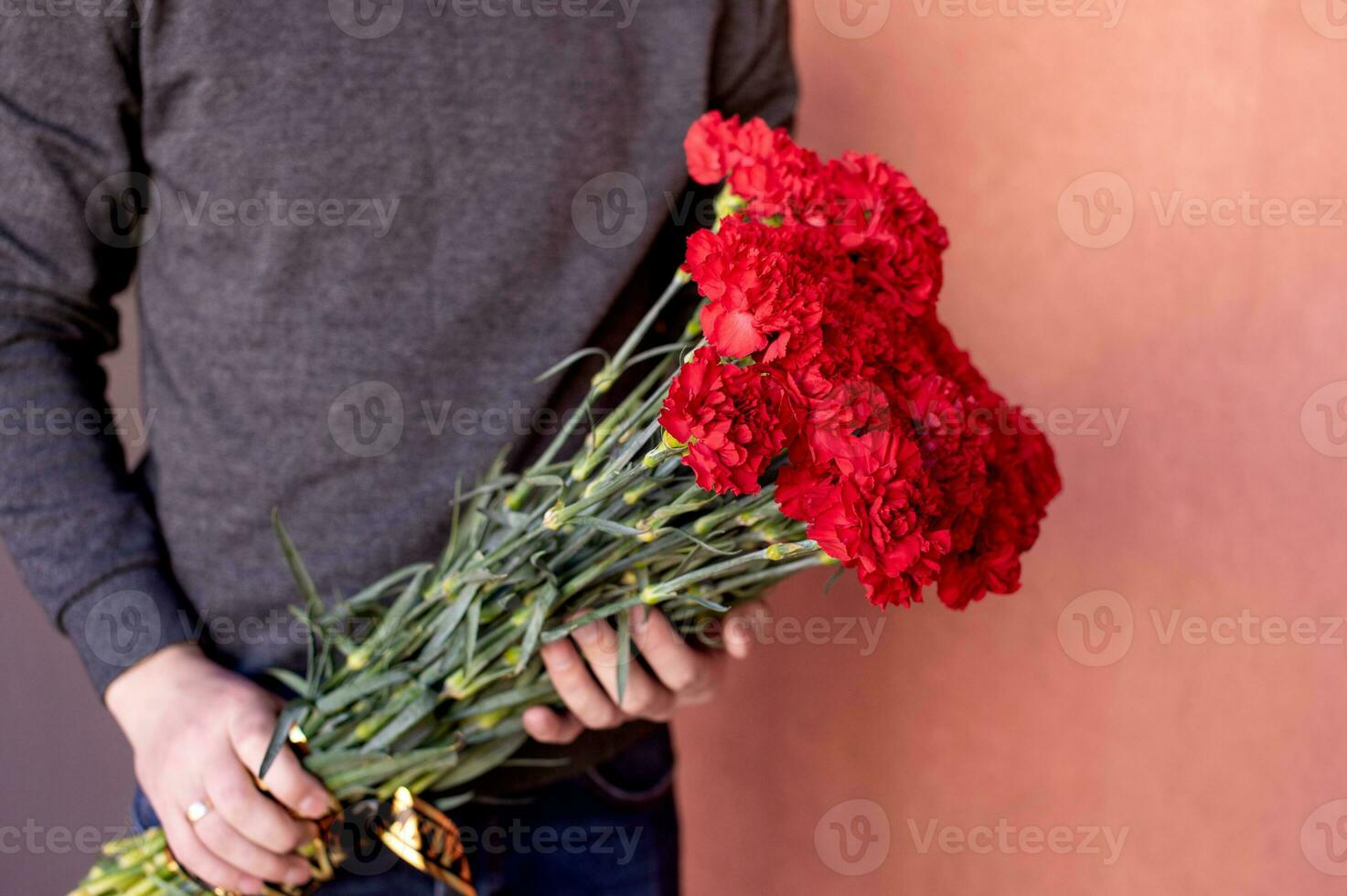 A large bouquet of red carnations with a black ribbon in the hands of a man photo