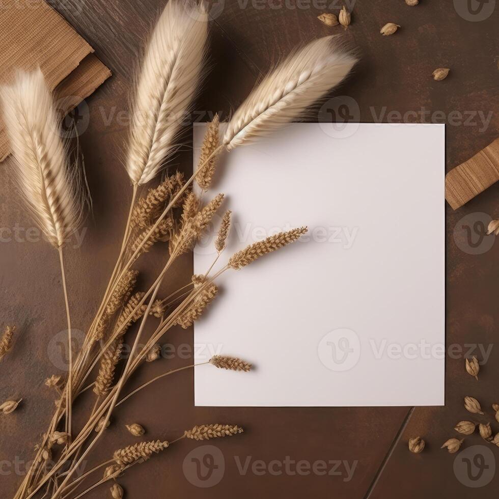 Top View of Blank White Paper with Reed Branch on Brown Wooden Background. Vintage Delicate Business or Wedding Card Design. . photo