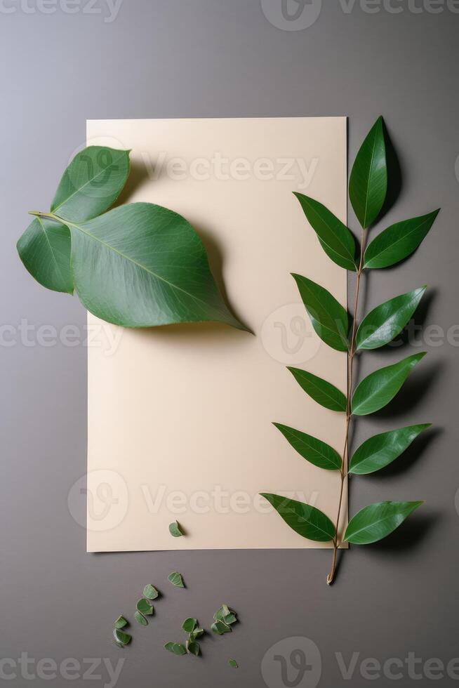 Top View of Blank Kraft Paper Mockup with Green Leaves on Gray Background. . photo