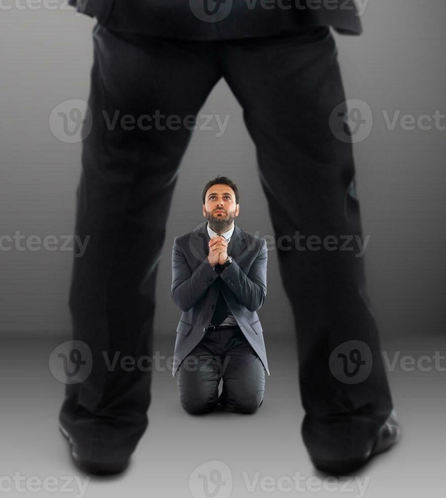Business man on his knees praying not to be dismissed photo