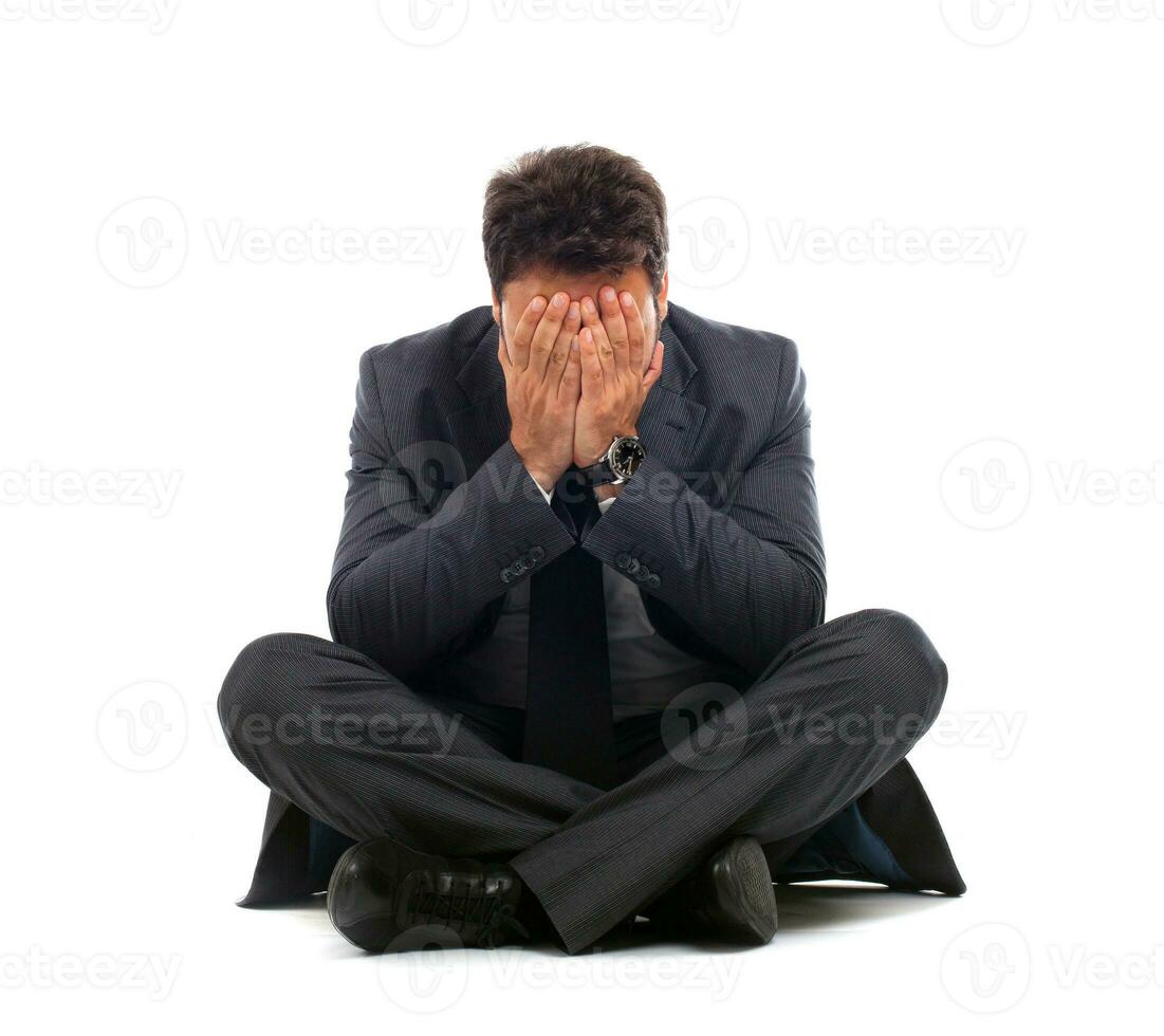 Depressed young businessman sitting on the ground photo