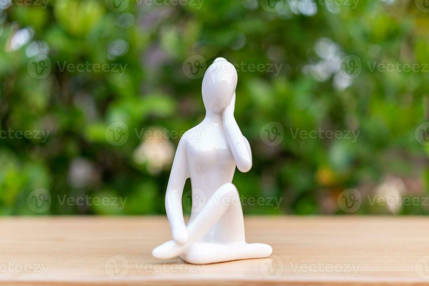 cerámico yoga figurilla de mujer haciendo yoga actitud en de madera piso y verde hoja antecedentes foto