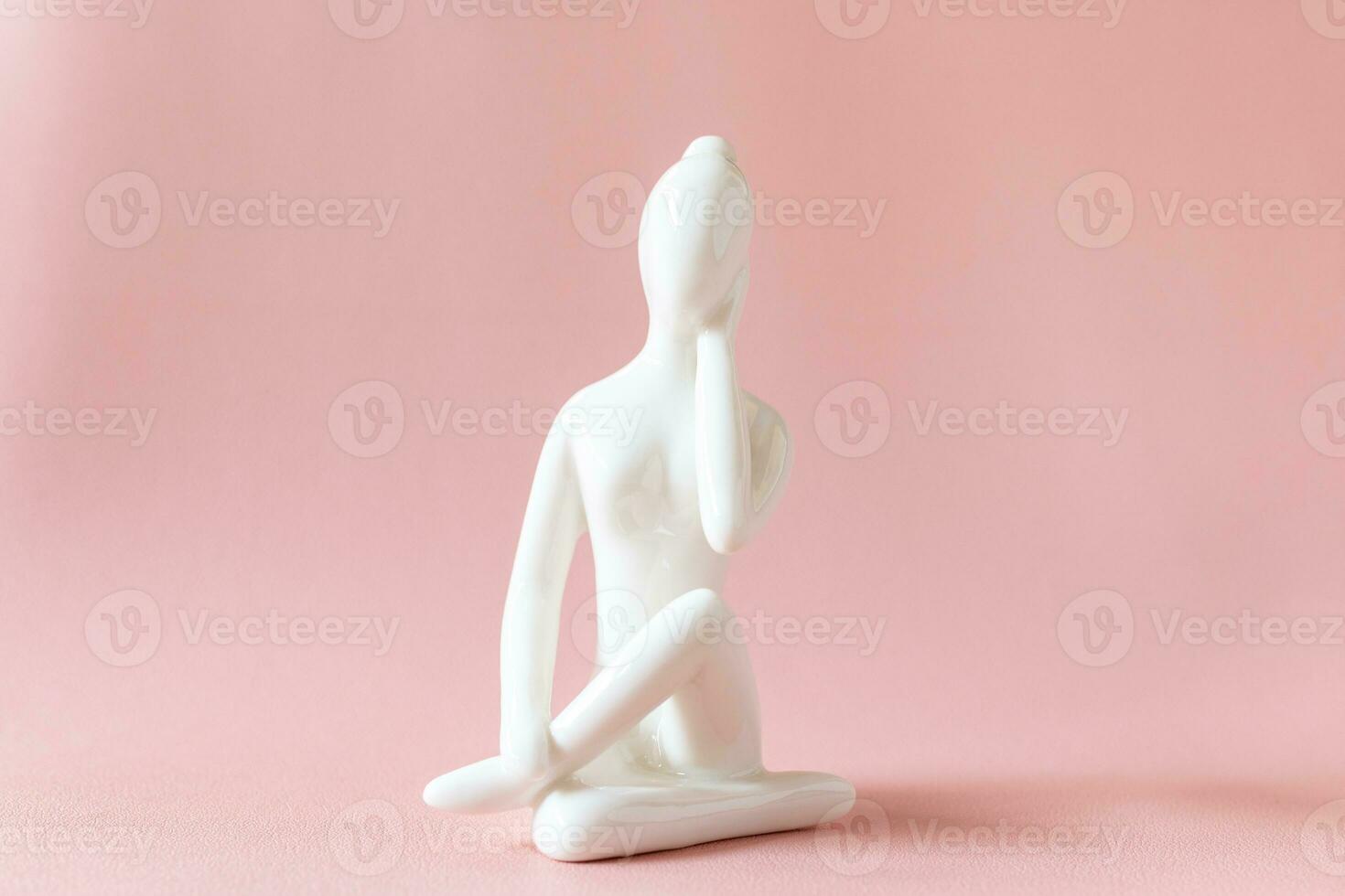 Ceramic Yoga Figurine of Woman doing yoga pose on pink background photo