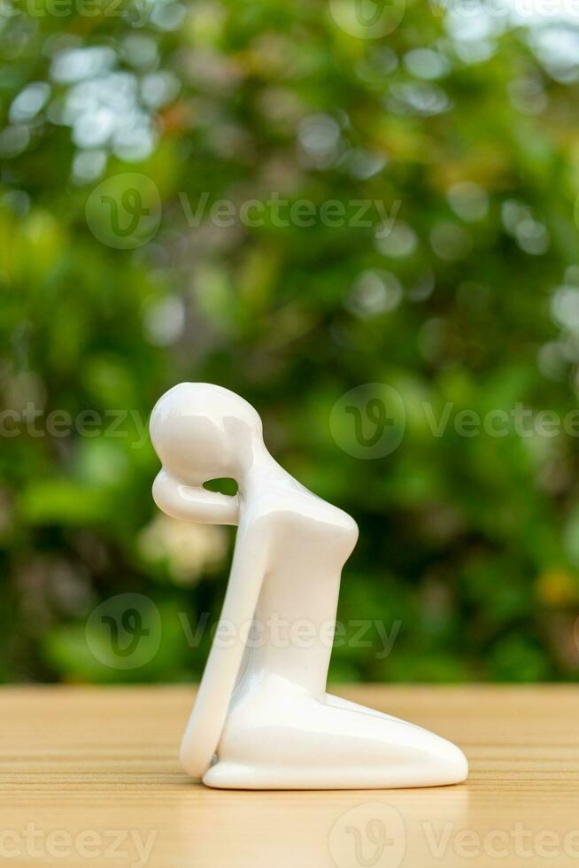 Ceramic Yoga Figurine of Woman doing yoga pose on wooden floor and green leaf  background photo