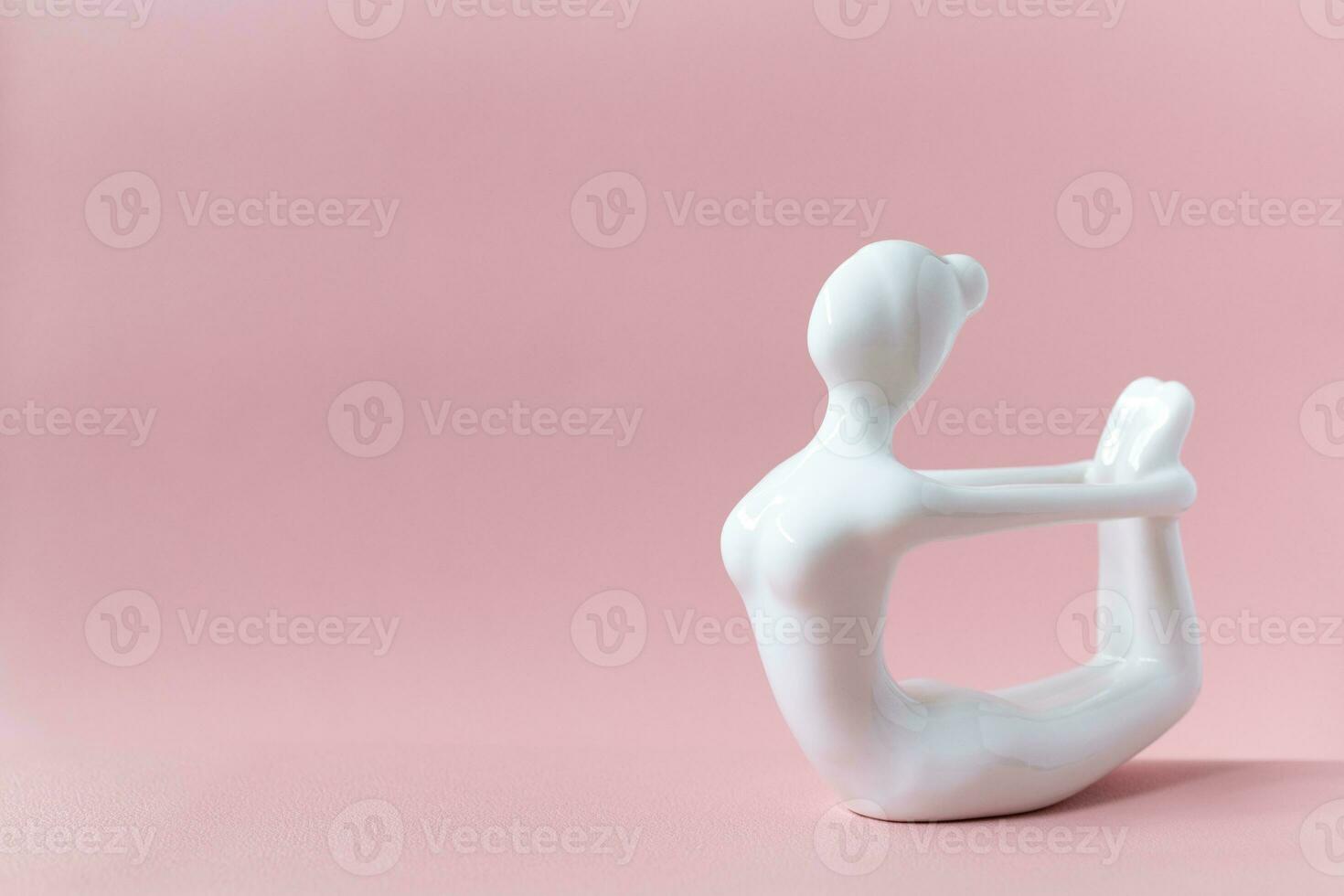 Ceramic Yoga Figurine of Woman doing yoga pose, Dhanurasana Bow Pose on pink background photo