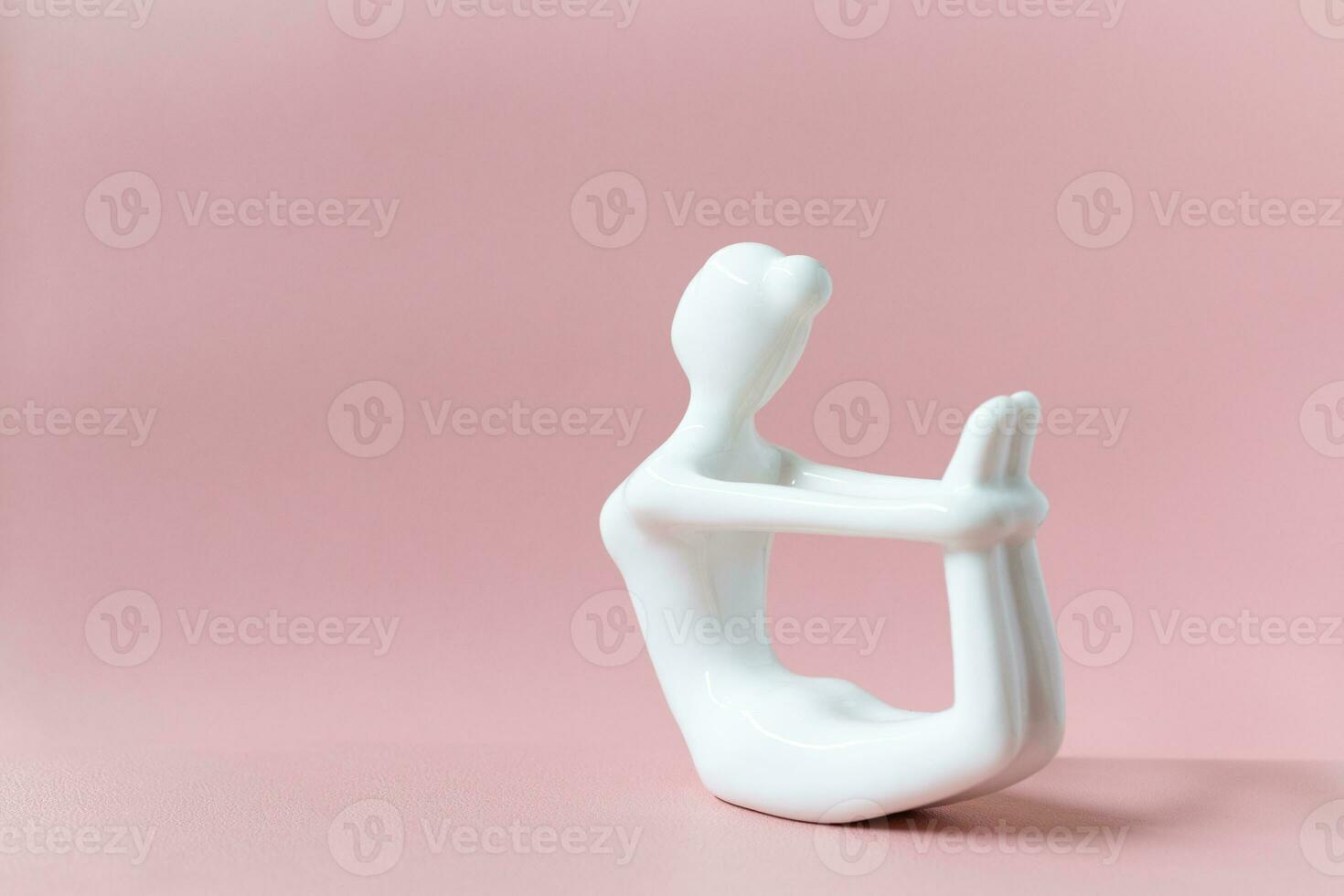 Ceramic Yoga Figurine of Woman doing yoga pose, Dhanurasana Bow Pose on pink background photo