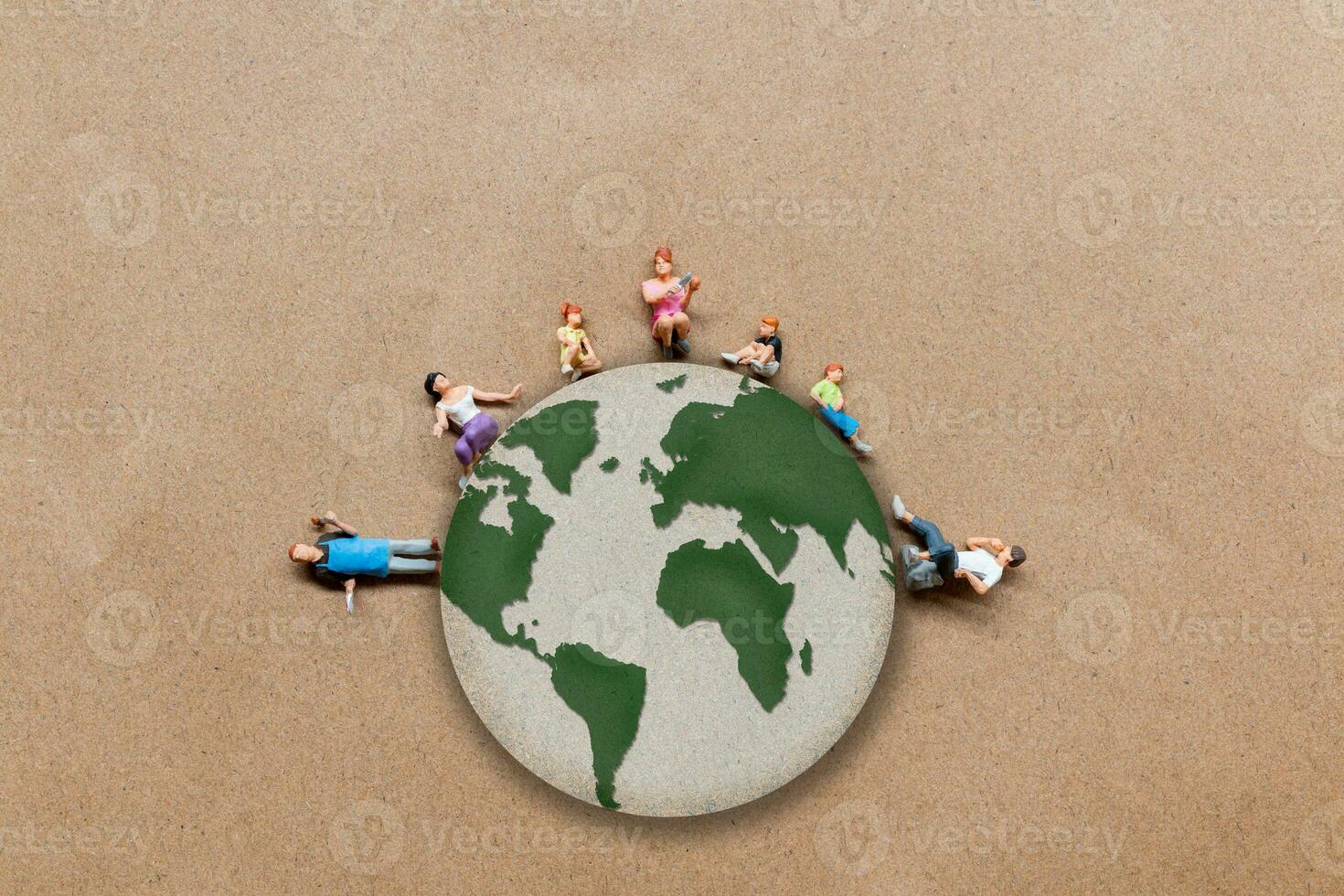 Miniature people standing on the globe with paper background photo