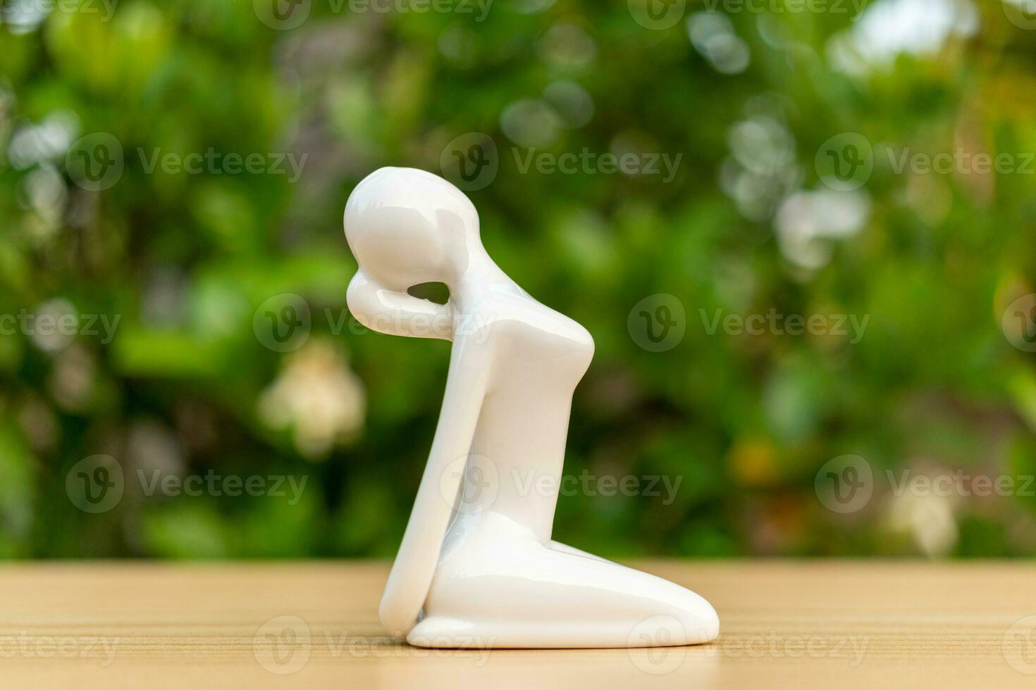 Ceramic Yoga Figurine of Woman doing yoga pose on wooden floor and green leaf  background photo