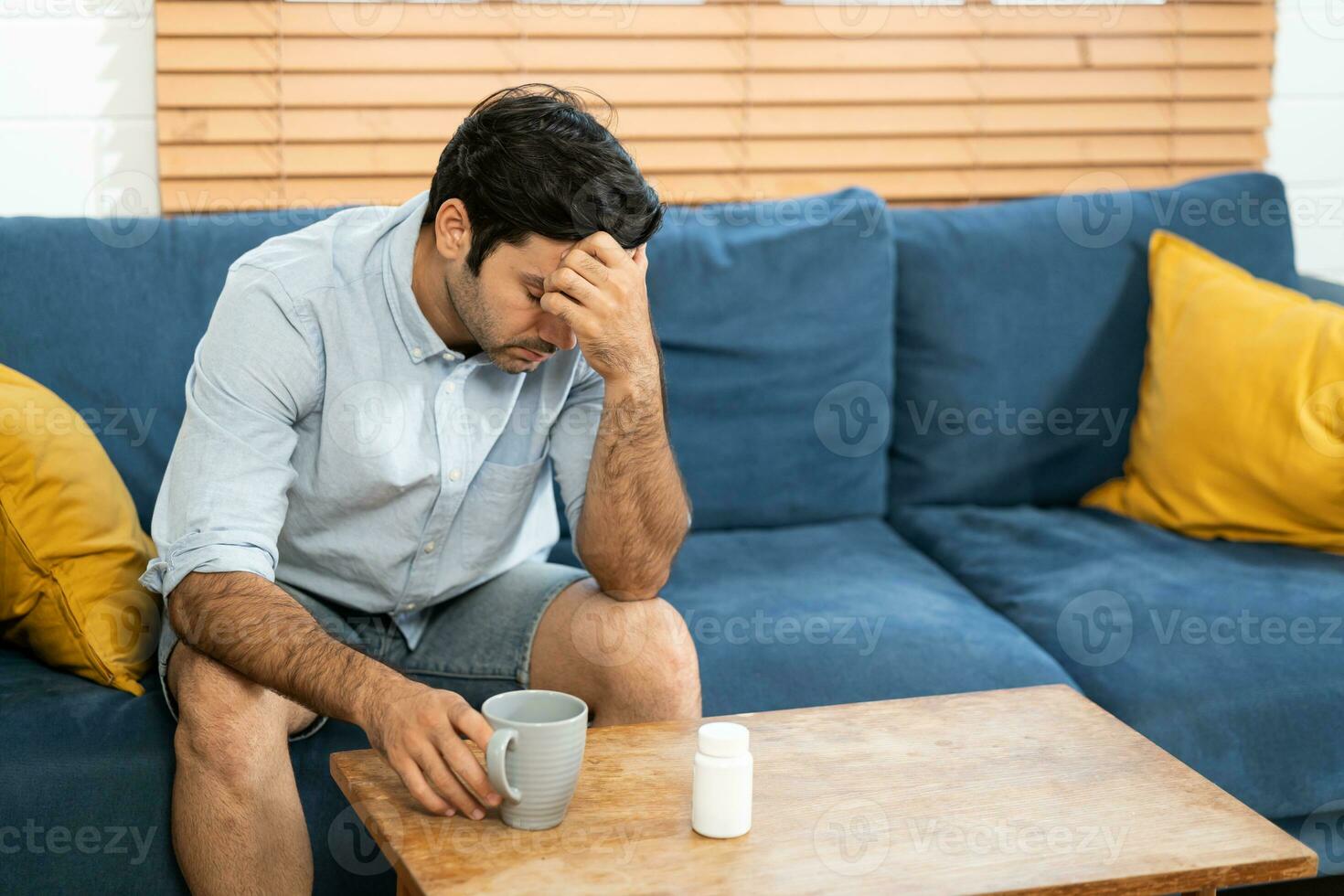 Unhappy man thinking about health or something bad on his sofa at home in the living room. upset man having problems, side view, copy space. Loneliness, depression, financial hangover concept. photo
