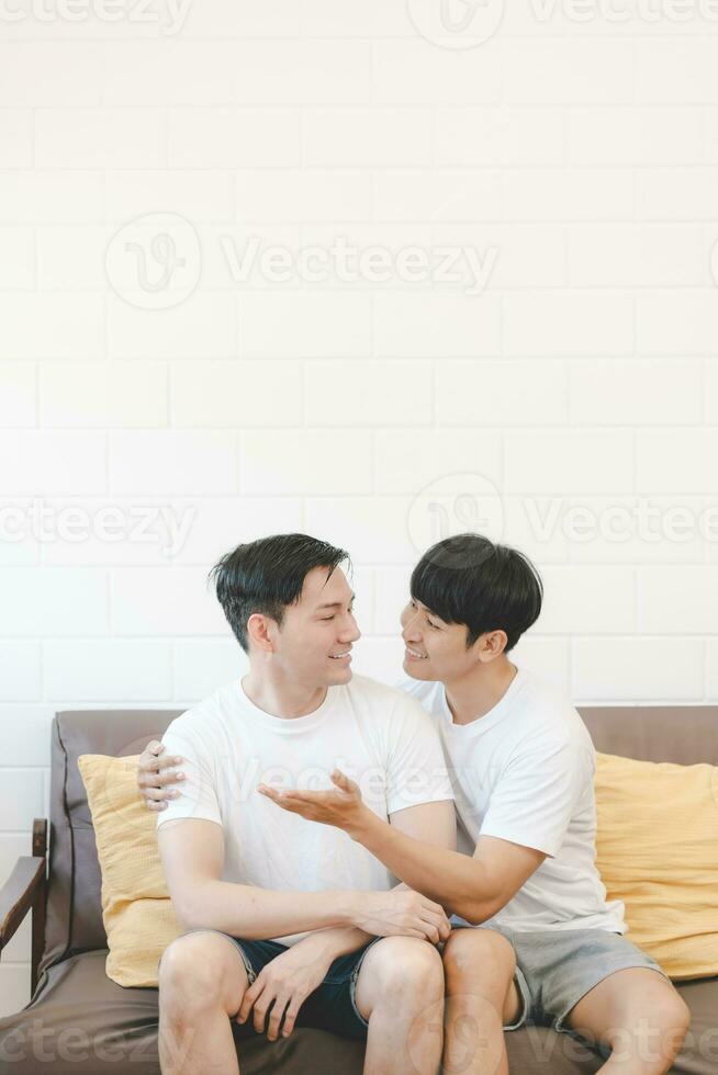 Happy Asian gay couple hug together on sofa. Asian LGBT couple embracing together at home. Diversity of LGBT relationships. A gay couple concept. LGBT multi relationship. photo