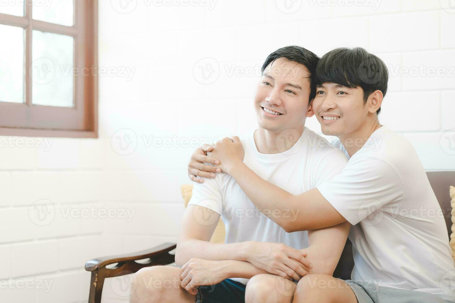 contento asiático gay Pareja abrazo juntos en sofá. asiático lgbt Pareja abrazando juntos a hogar. diversidad de lgbt relaciones un gay Pareja concepto. lgbt multi relación. foto