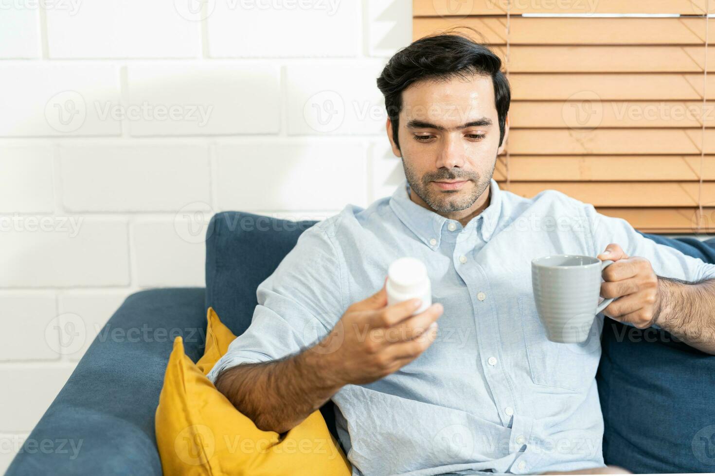 Unhappy man thinking about health or something bad on his sofa at home in the living room. upset man having problems, side view, copy space. Loneliness, depression, financial hangover concept. photo
