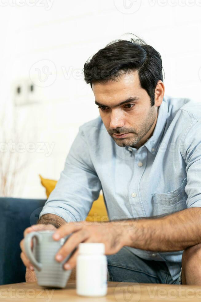 Unhappy man thinking about health or something bad on his sofa at home in the living room. upset man having problems, side view, copy space. Loneliness, depression, financial hangover concept. photo