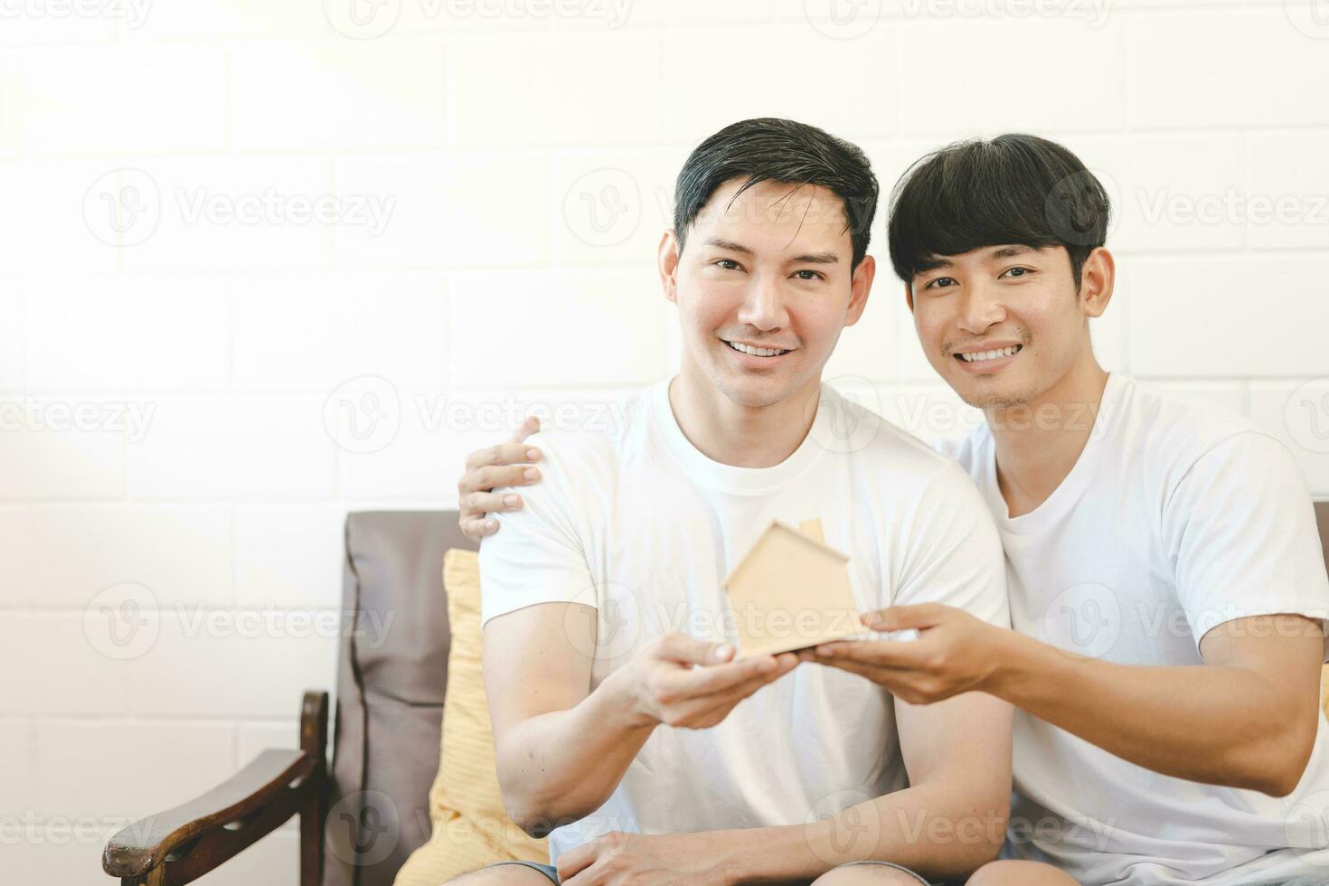 Asian Gay Couple Buying New Dream House Or Property with house model. Concept for marriage, loan, finance, insurance, mortgage, real estate and property. photo