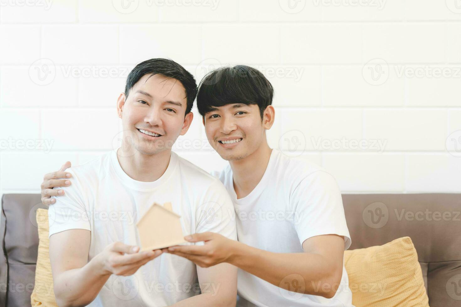 Asian Gay Couple Buying New Dream House Or Property with house model. Concept for marriage, loan, finance, insurance, mortgage, real estate and property. photo