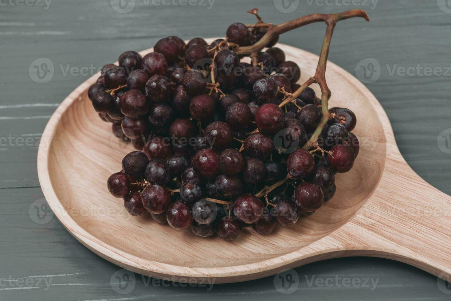 Fresco vistoso sano orgánico sin semillas rojo uvas grumos en madera plato. foto