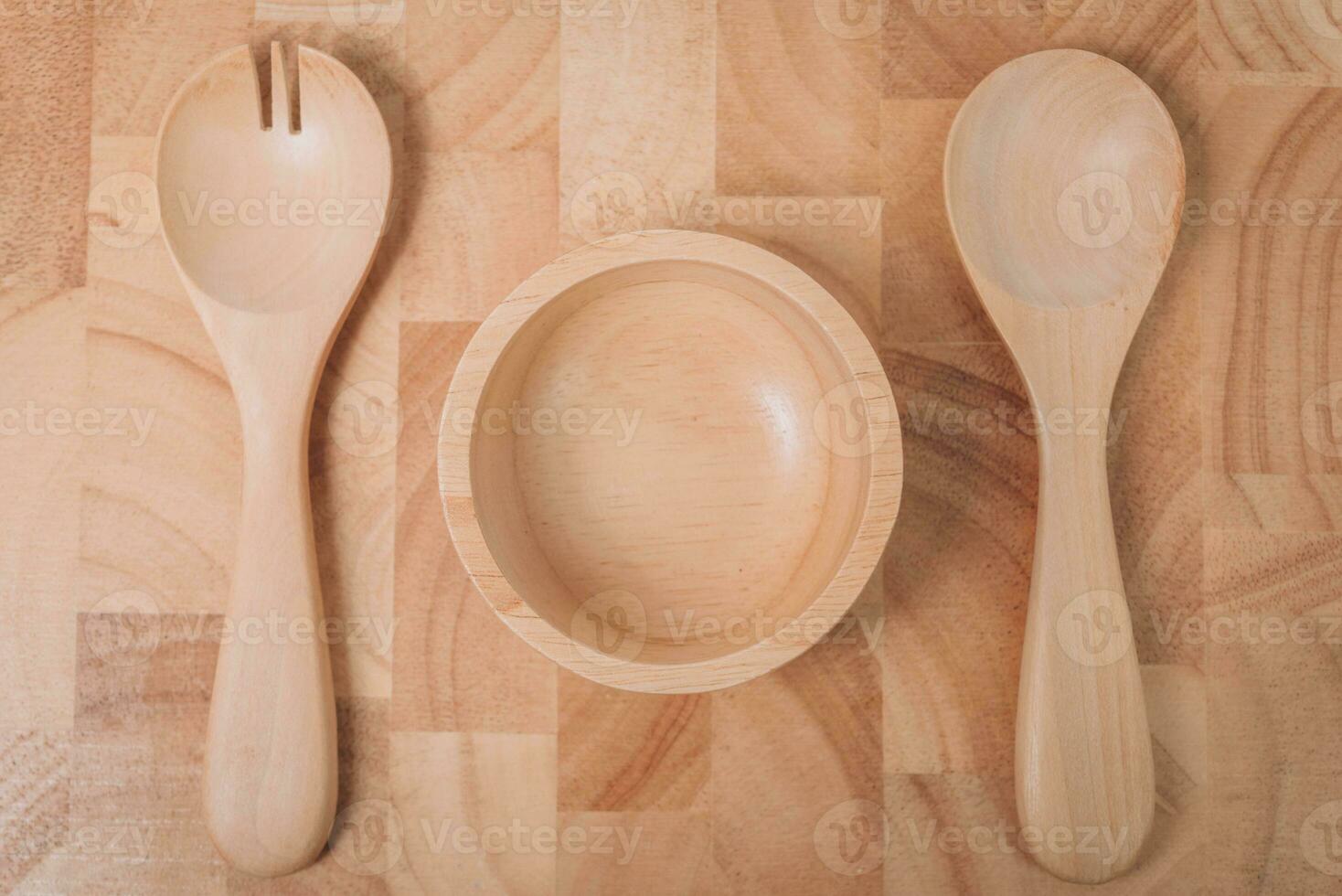 conjunto de tenedor, cuchara y plato madera en de madera mesa foto