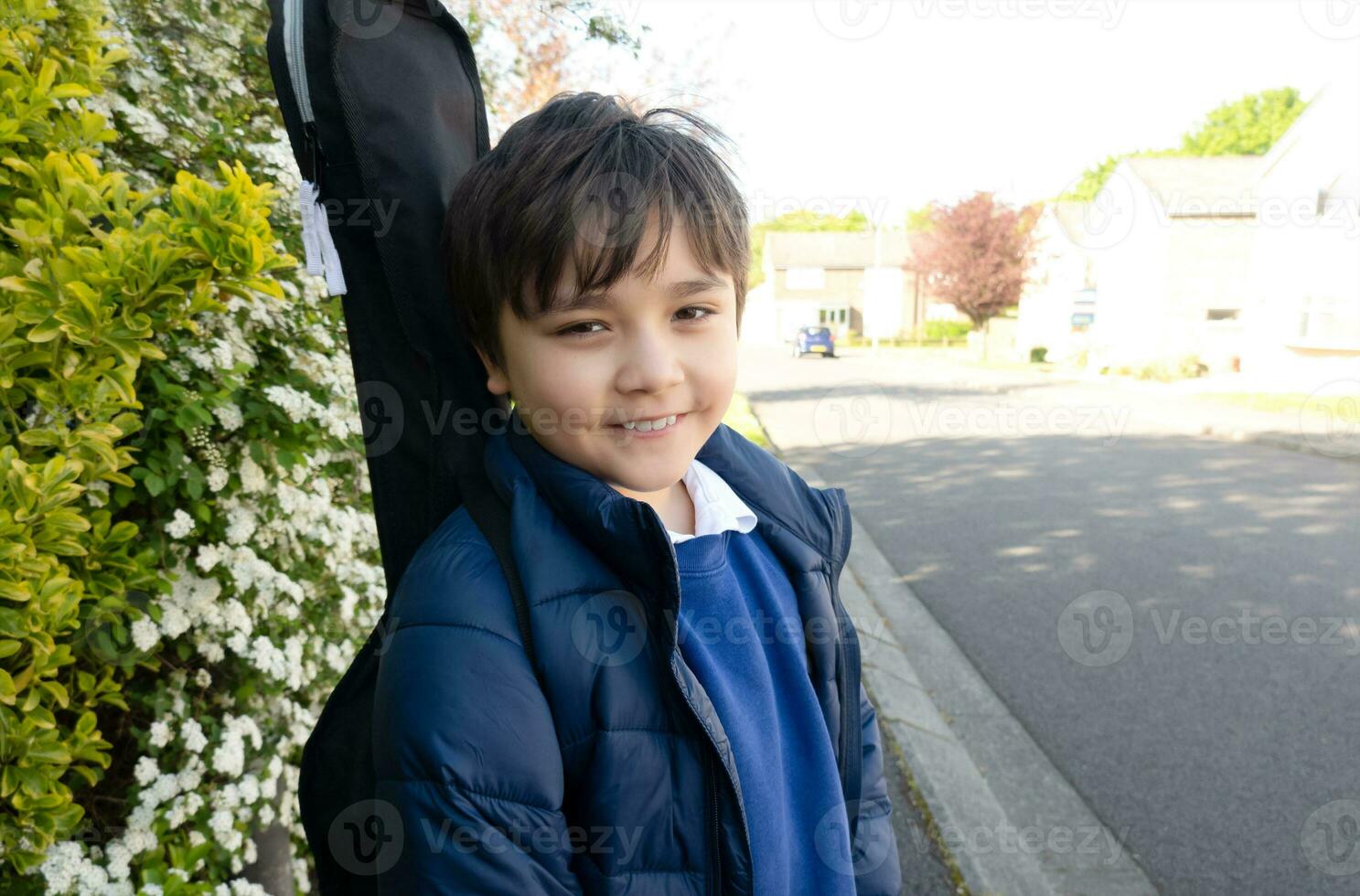 espalda a colegio concepto,feliz niño con sonriente cara yendo a colegio con guitarra caso, alto llave retrato linda joven chico en pie en sendero esperando para autobús. foto