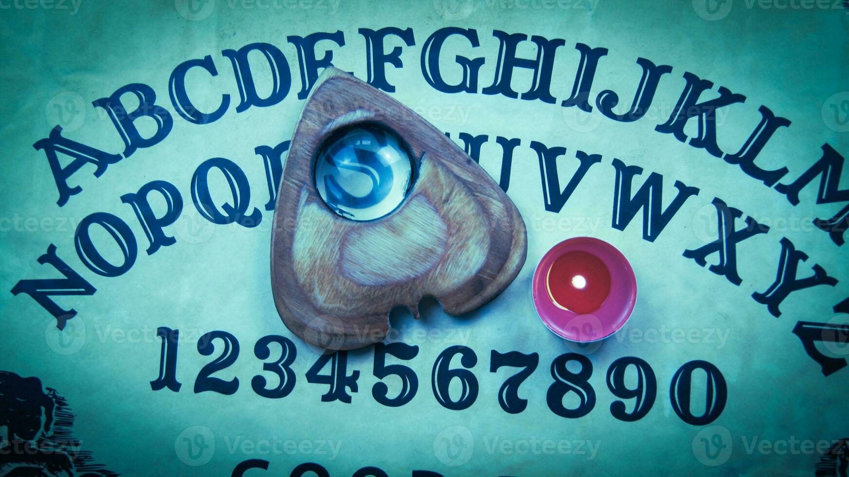 Halloween game with Ouija board. Pointer with magnifying glass and tea red candle on planchette. photo