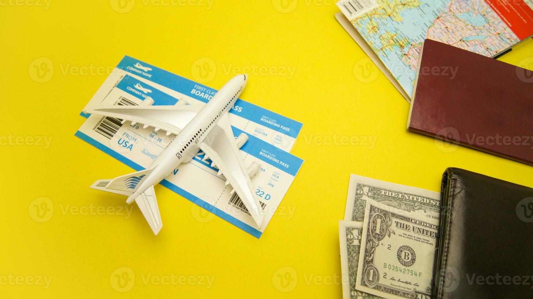 Plane, boarding passes, wallet, map, money and passport on yellow background. Travel Holiday Composition photo