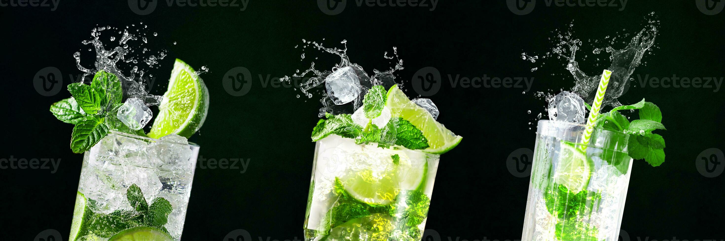 Glasses of Mojito with splashes and flying ice cubes on black and green background in bar photo