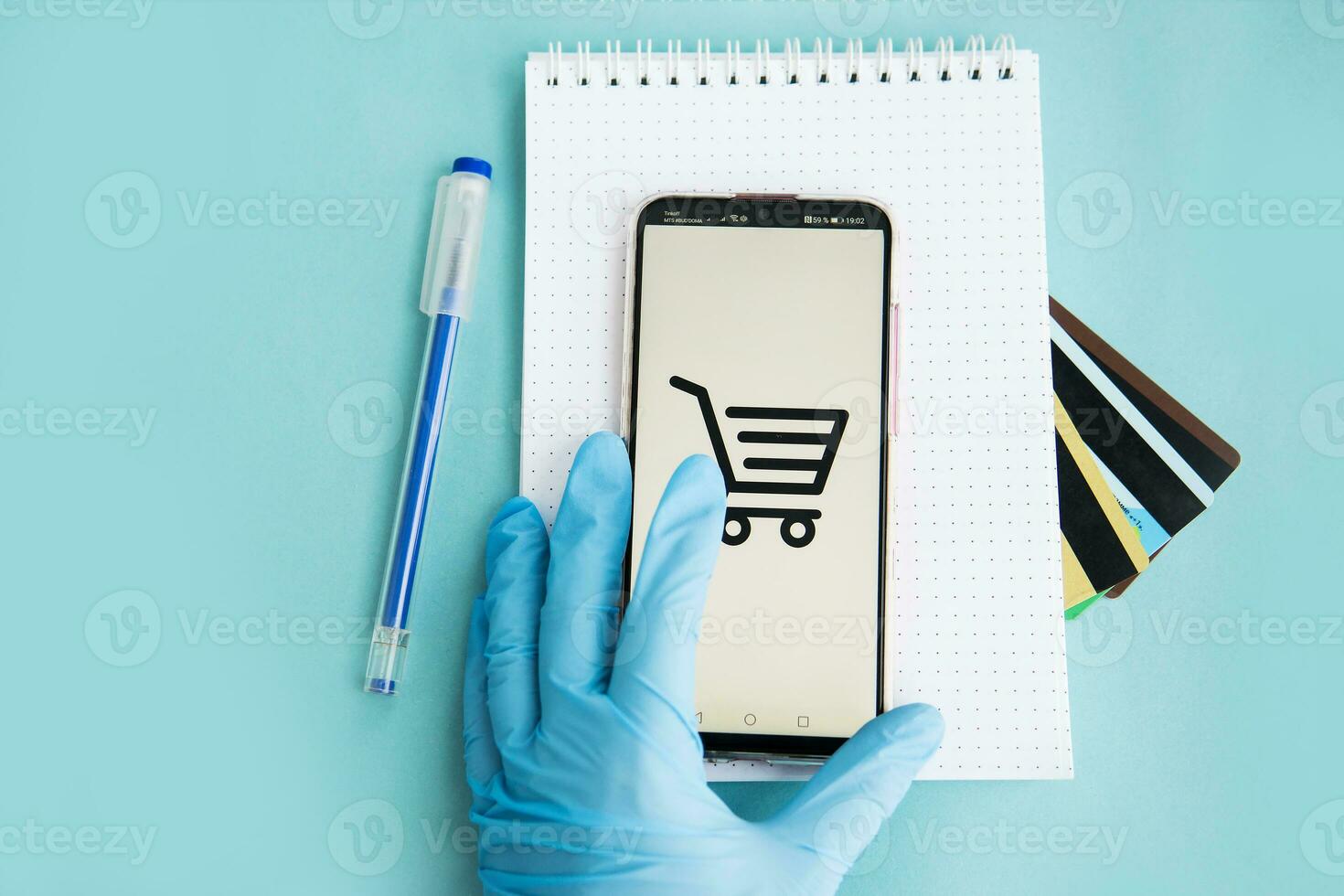 Close-up of hands in medical gloves with a smartphone. Online shopping, online banking, online payment. Payment with plastic cards. Flat Lay on blue background. photo