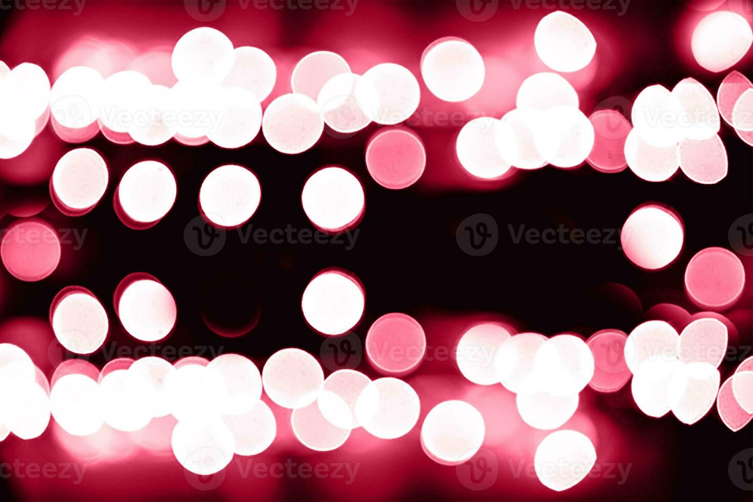 Blurry garland lights on a dark background. Festive Christmas and New Year background. Soft focus. Image toned in color of the year 2023 viva magenta photo