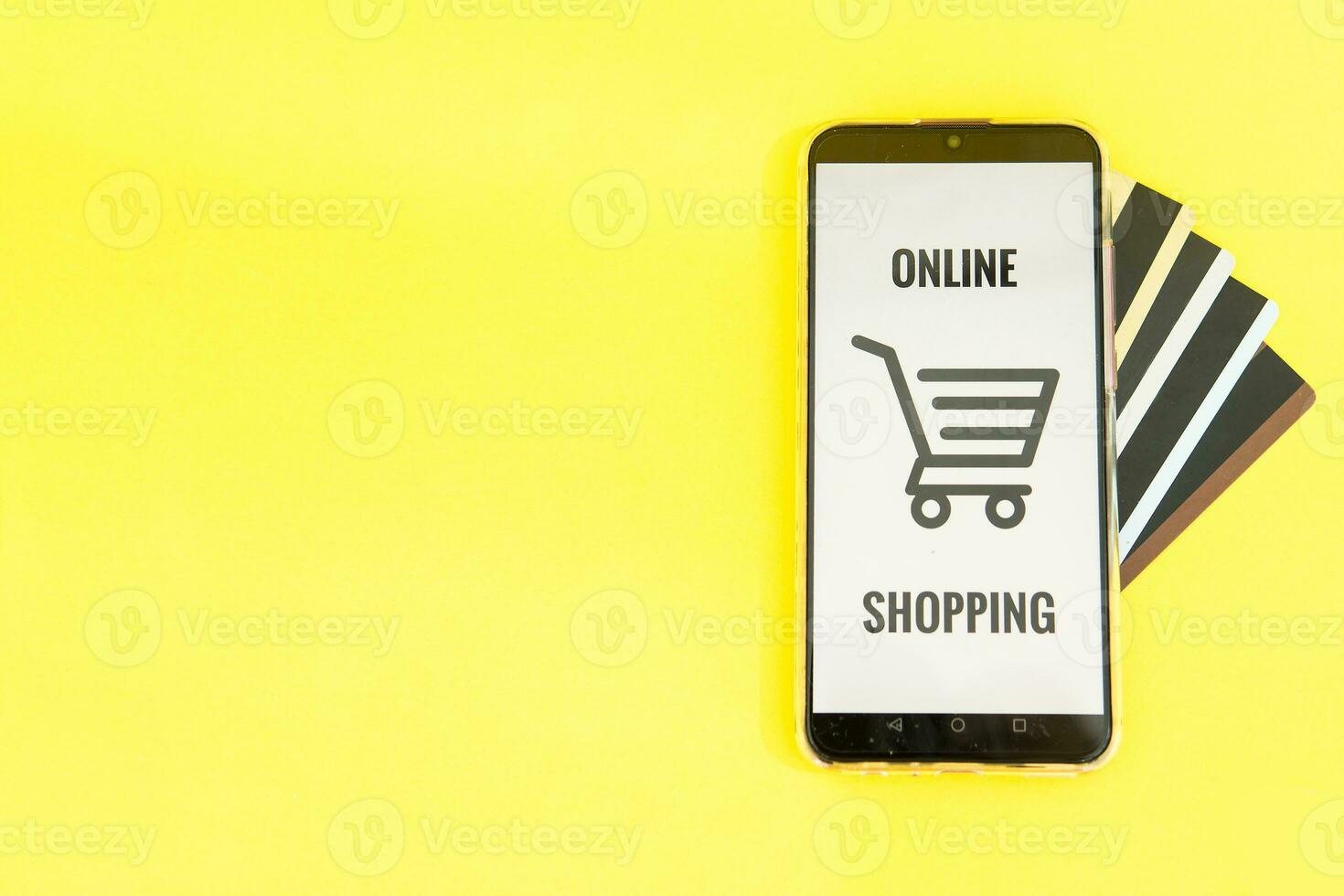 Smartphone with the inscription-online shopping close-up. Online shopping, online banking, online payment. Payment with plastic cards. Flat Ley on a yellow background. photo