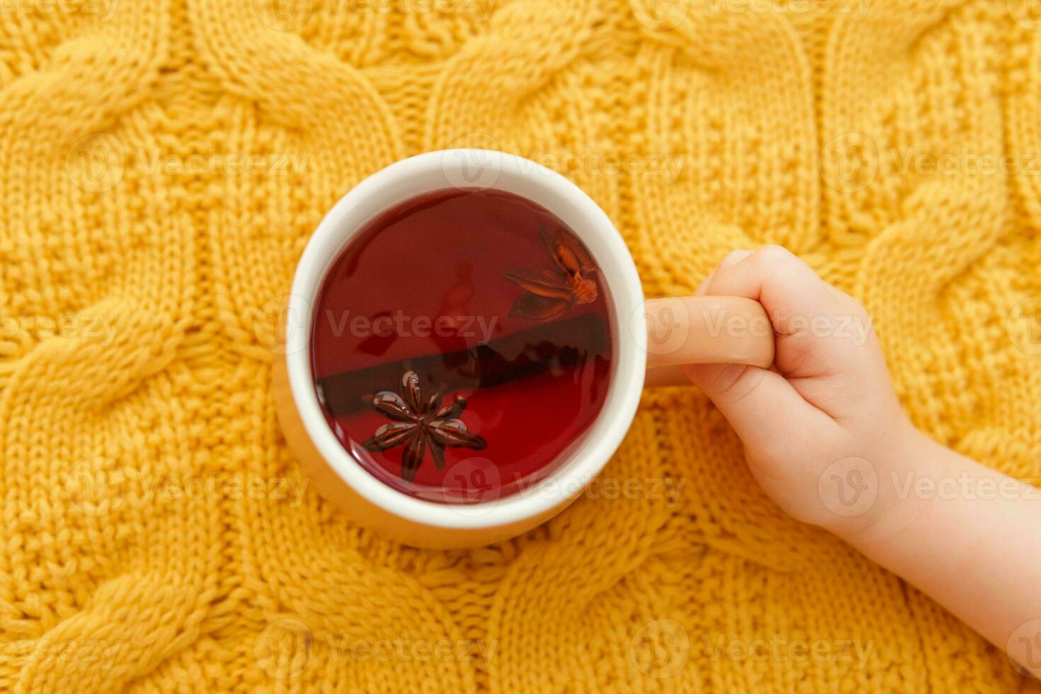 Karkade tea in an orange cup on an orange knitted background. The concept of the autumn season, natural colors. Red fruit tea. photo