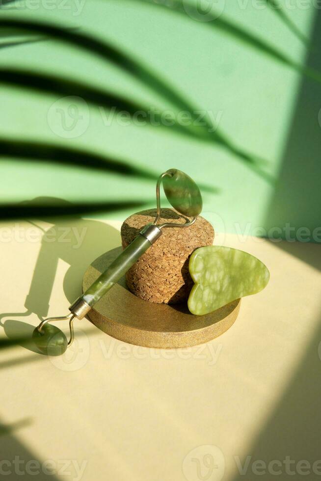 Jade Gua sha scraper and facial massager on beige background. Lifting and toning treatment at home. photo