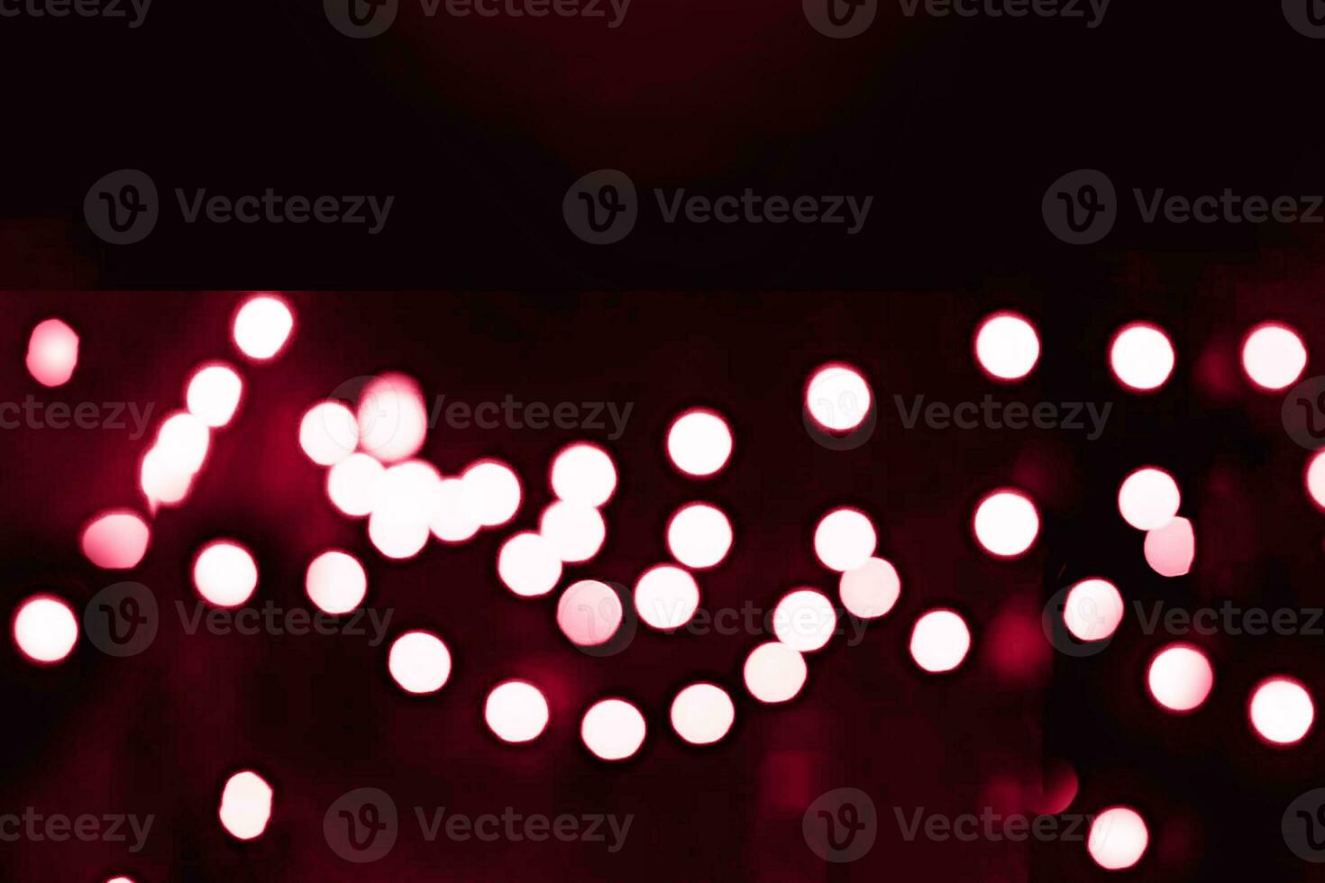 Blurry garland lights on a dark background. Festive Christmas and New Year background. Soft focus. Image toned in color of the year 2023 viva magenta photo