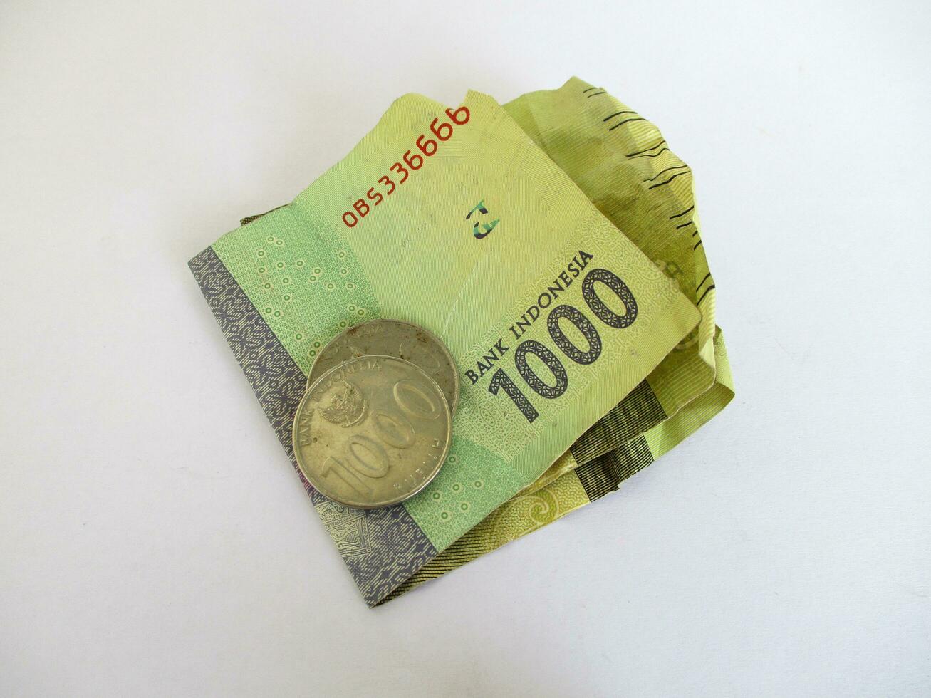 Denominations of one thousand rupiah banknotes and coins on a white background. Symbolizes change, poor, or cheap money in Indonesia. photo