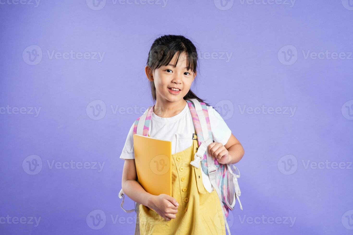 cute asian schoolgirl posing on purple background photo