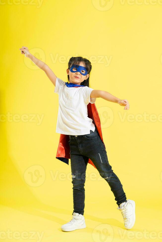 Portrait of little girl dressed up as a hero, isolated on yellow background photo