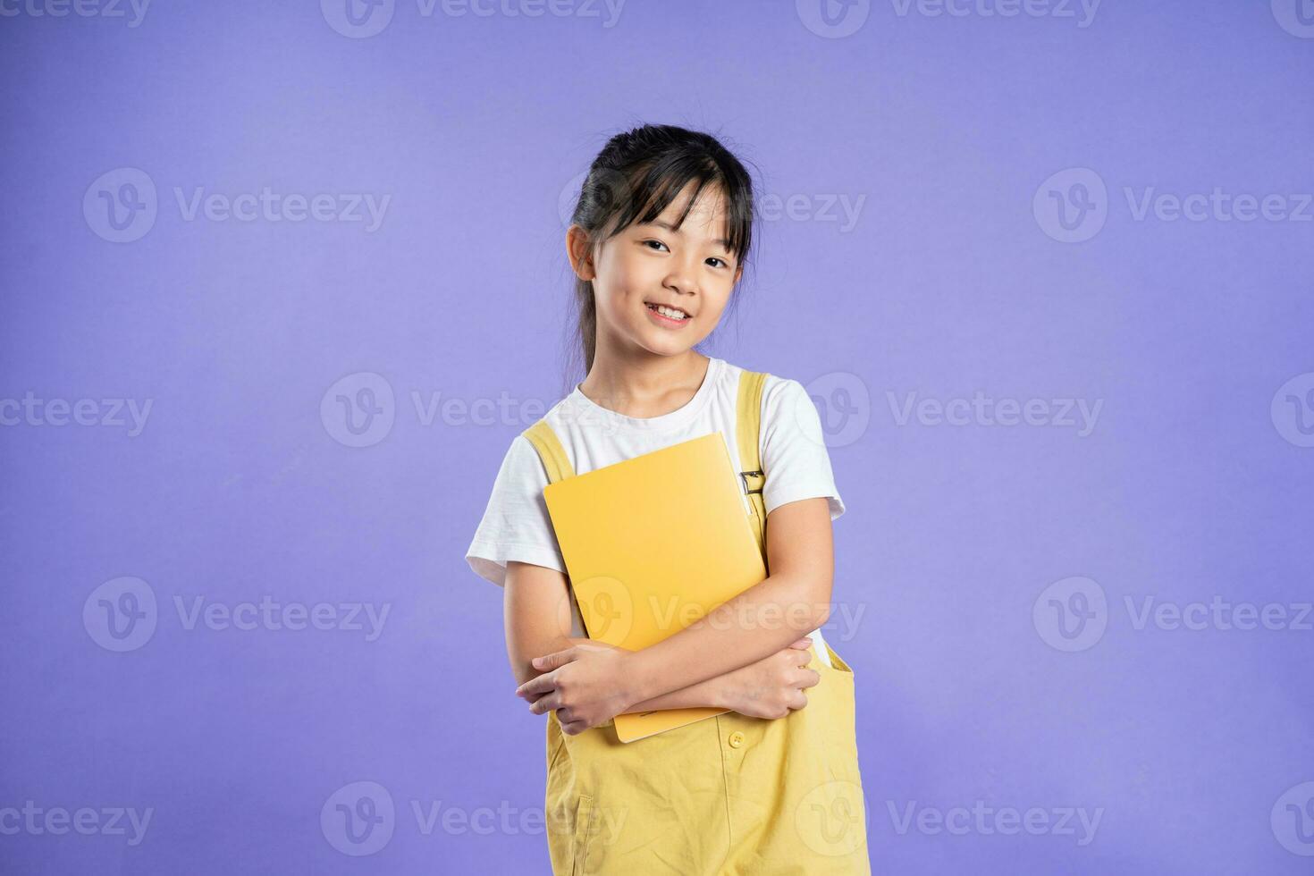 cute asian schoolgirl posing on purple background photo