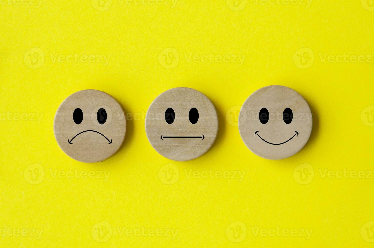 Happy, sad and neutral emoticon faces on wooden circle with yellow background cover. Customer feedback, satisfaction and evaluation concept photo