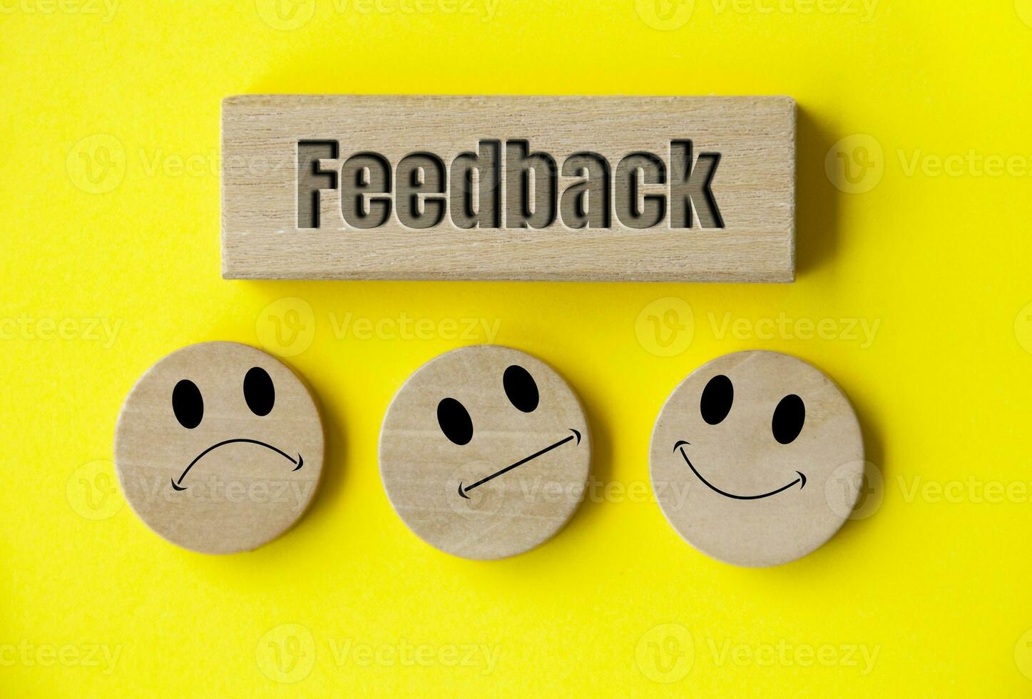 Feedback text on wooden block with happy, sad and neutral emoticon faces on wooden circle with white background cover. Customer feedback, satisfaction and evaluation concept. photo