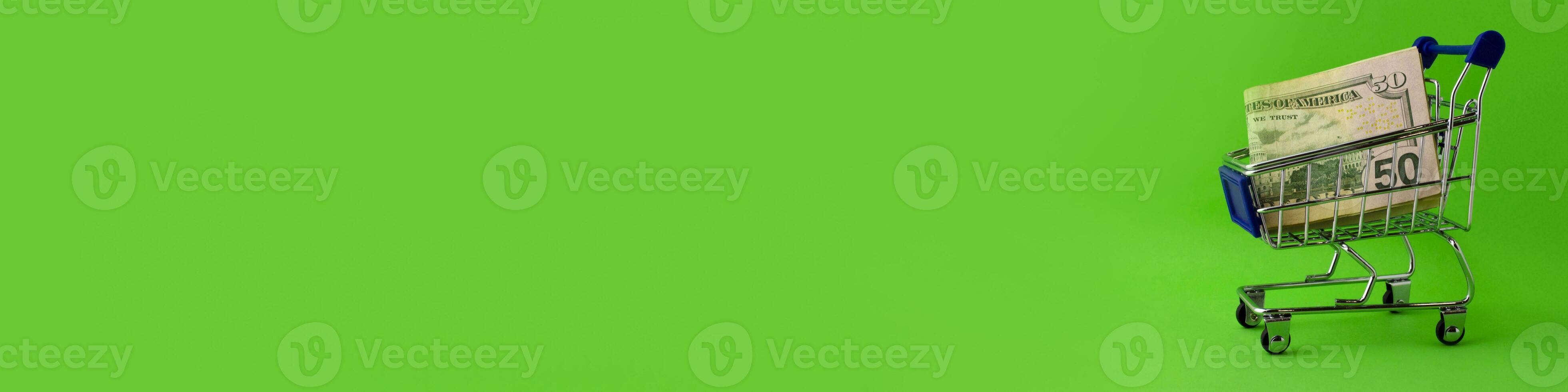 Banner. Shopping cart with 50 dollar bills on a green background. photo