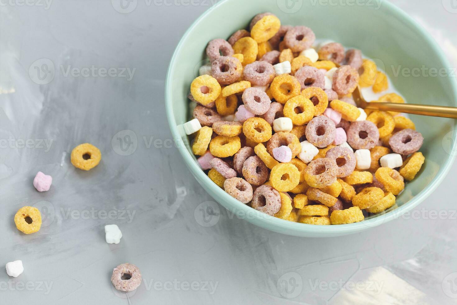 Multi colored fruit loops in a bowl with spoon photo