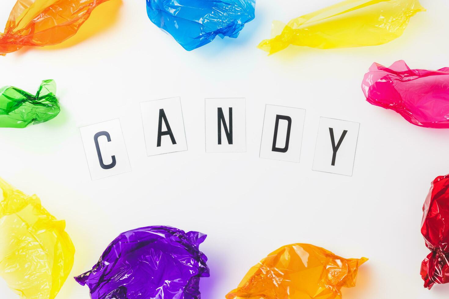 Colorful candy wrappers and text CANDY on white background photo