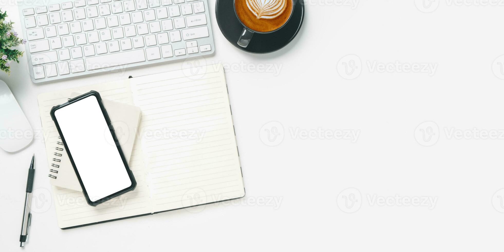 parte superior vista, blanco oficina escritorio con teclado, blanco pantalla inteligente teléfono, computadora portátil, bolígrafo y taza de café, Copiar espacio, burlarse de arriba. foto