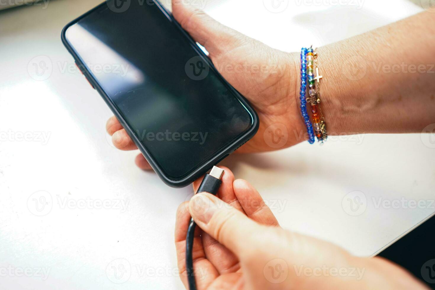 Person plugging the phone to the charger. Charging smartphone. Smartphone in hand. Smartphone loading. Loading the battery. photo
