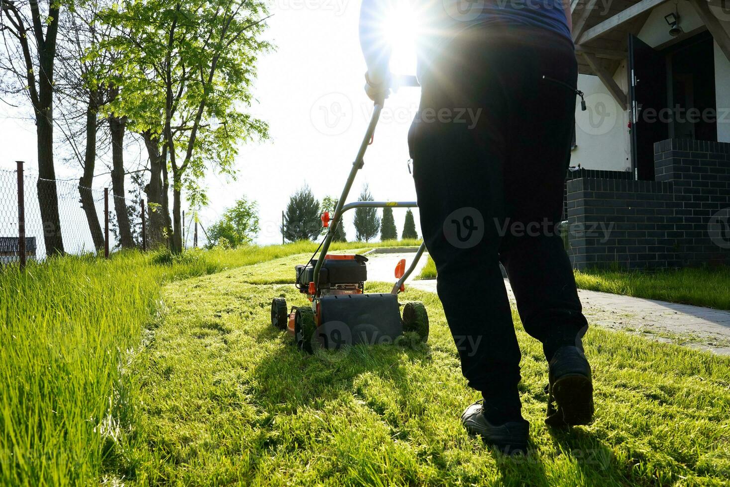 césped siega. persona siega el césped con naranja cortacésped siega en el verano en soleado día. foto