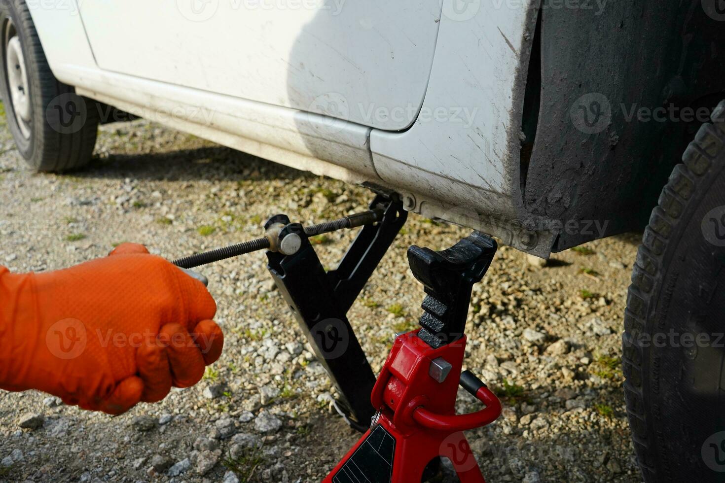 Car lifted on jack. Mechanic lifting up the car with car jack. Tire change. Mechanic changing tire in the car. photo