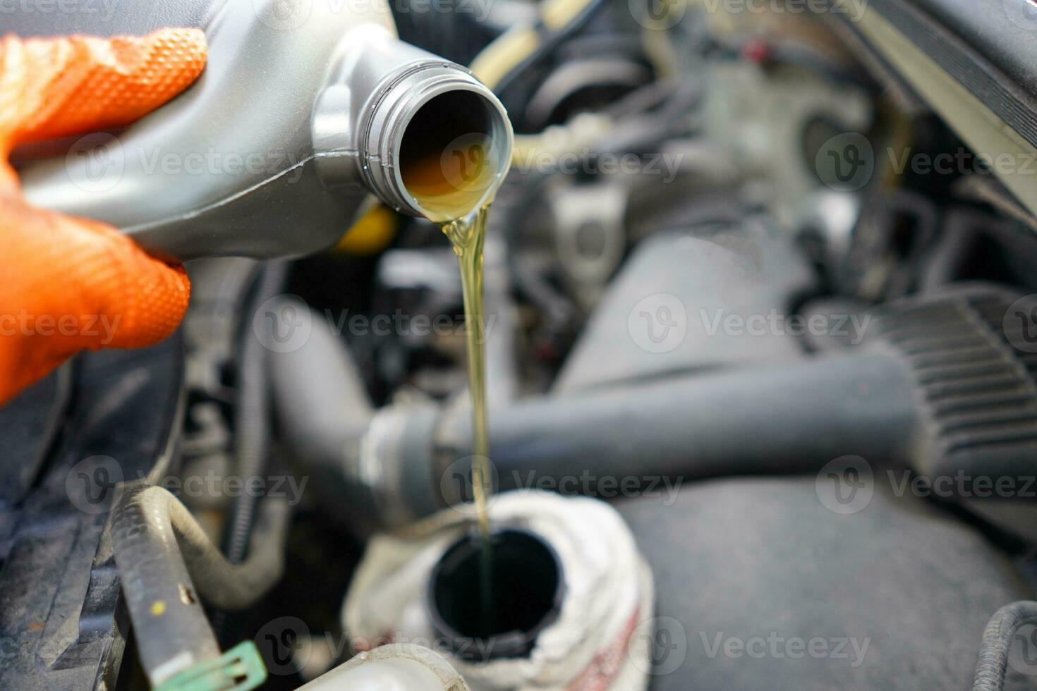 Pouring oil to the car. Car mechanic holding a bottle of oil in hand over the engine. Car engine oil. Topping up car oil. photo