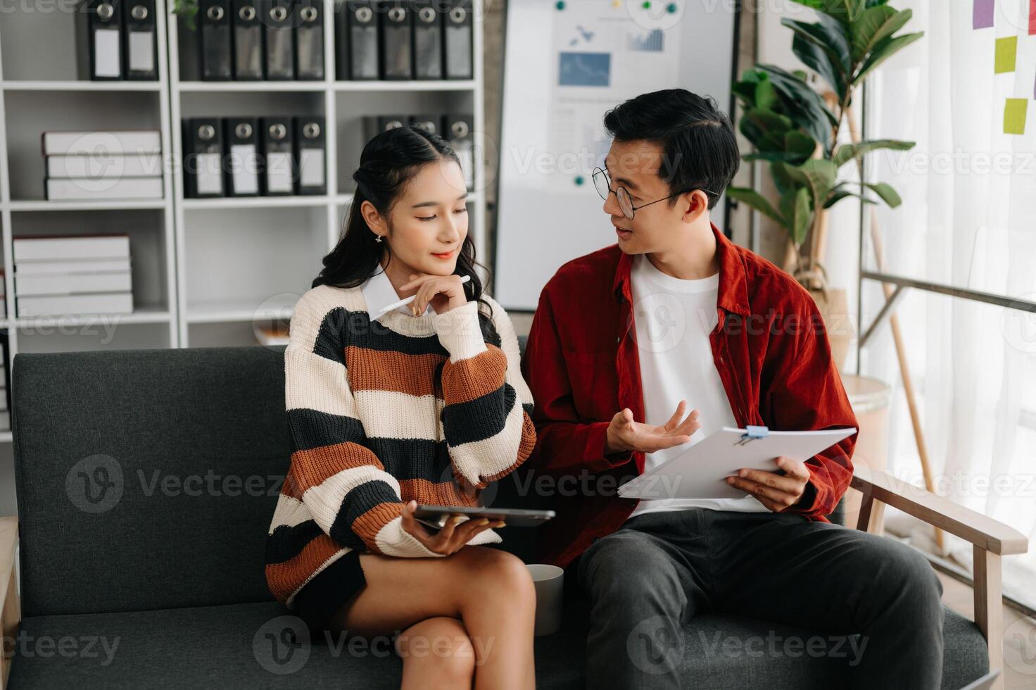 Businesswomen work and discuss their business plans. A Human employee explains and shows her colleague the results paper in modern office. photo